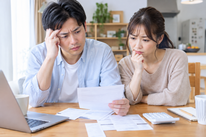 請求書を確認しながら家計について悩む若い夫婦
